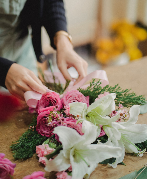 Florista realizando ramo de liliums blancos y rosas rosadas con verdes variados